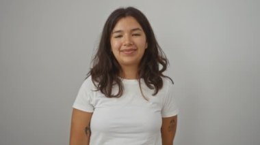 Genç İspanyol kadın dili açık duruyor, beyaz tişört giyiyor, arka planda komik ve mutlu bir ifade sergiliyor, eğlence için dilini dışarı çıkarıyor.