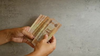 Birleşik Arap Emirlikleri 'nde finansal işlemleri vurgulayan somut bir arkaplan karşısında uae dirham banknotları sayan adam.