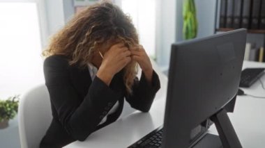 Ofiste çalışan bir kadın masasında bilgisayarla otururken stresli görünüyor.