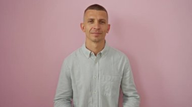 Elleri yüreğinde, pembe arka planda açık mavi gömlek giyen genç bir adam minnettarlığını ve takdirini gösteriyor..