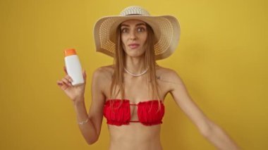 Bikinili kadın elinde güneş kremi tutuyordu. Baş ağrısı ve öfkeli ifadeyle izole edilmiş sarı arka plan.