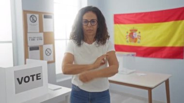 İspanyol orta yaşlı kadın oy pusulasının başında gergin ve onaylanmayan bir ifadeyle İspanyol seçim üniversitesinde duruyor.