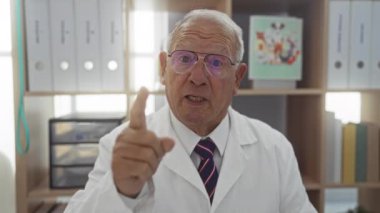 Beyaz önlüklü ve kravatlı yaşlı bir adam iyi organize olmuş bir klinikte arka planda raflar ve dosya klasörleri ile gülümseyerek veteriner ya da doktor ayarları için mükemmel..