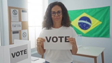 Orta yaşlı İspanyol kadının elindeki oy kağıdı Brezilya seçim okulunda gülümseyerek, dostça ve mükemmel bir jest gösteriyor.