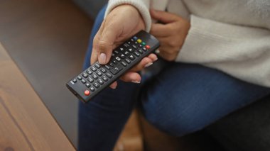 Uzaktan kumandalı orta yaşlı bir kadın, sıradan bir ortamda evde oturuyor..