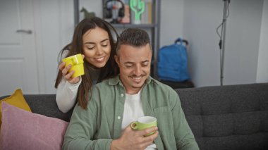 Sevgi dolu bir çift, modern bir oturma odasında kahve fincanlarıyla sıcak bir anın tadını çıkarıyor..