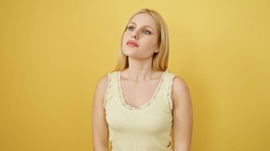 Sarışın kadın sarı bir duvara poz veriyor, güzelliğini ve sadeliğini nazikçe anlatıyor..