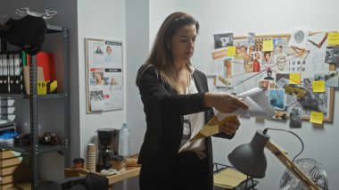 Odaklanmış bir İspanyol kadın dedektif dağınık bir polis karakolunda kanıtları analiz ediyor..