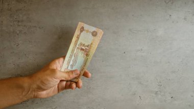 Somut bir zemine karşı el ele tutuşmak, Birleşik Arap Emirlikleri 'nin belirgin para birimini sergilemek..