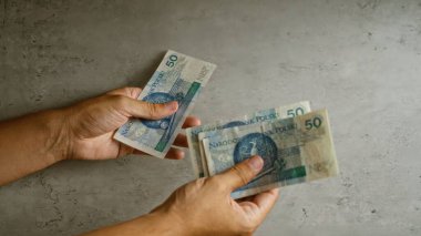 Somut bir arka planda, maddi işlemleri veya ödemeleri resmeden, cilalı zloti banknotları el ele tutuşup değiş tokuş etmek.