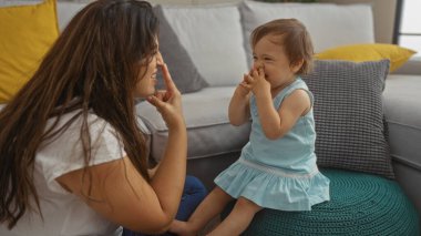 Anne ve küçük kızı sıcak bir oturma odasında birbirine dokunup gülüyor sevgi ve neşe dolu hassas bir aile anı yaratıyor..