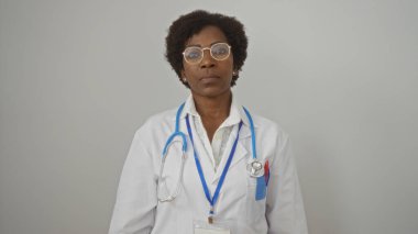 Orta yaşlı, kıvırcık saçlı, gözlüklü ve stetoskop takan beyaz bir arka planda izole edilmiş Amerikalı kadın doktor.