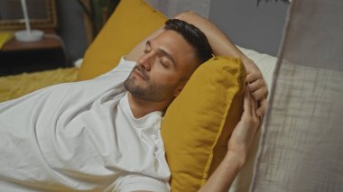 Sarı bir yastıkta dinlenen İspanyol bir adam..