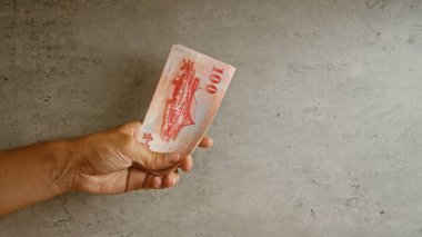 Elle tutulan Tayvan doları, somut bir zemine karşı, yakın plan çekimde 100 twd 'lik banknotu gösteriyor.