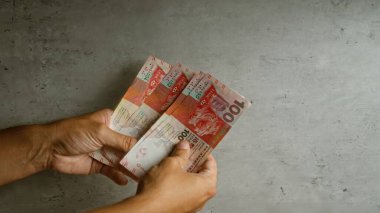 Duvara karşı Hong Kong doları sayan bir adam ellerinde renkli banknotlar sergiliyor..