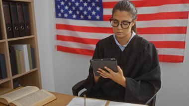 Genç kadın avukat, Amerikan bayrağıyla ofiste tablet kullanıyor.
