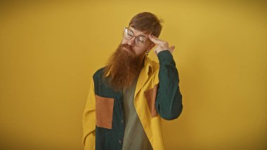 Sakallı dalgın kızıl saçlı adam sarı arka planda izole edilmiş.