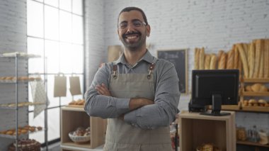 Pastanede bıyıklı genç İspanyol adam kollarını kavuşturup gülümsüyor.