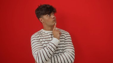 Çekici İspanyol adam kırmızı arka planda parmakları çenesinde düşünüyor..