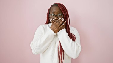 Pembe arka planda örgü örmüş, şaşırmış bir Afrikalı Amerikalı kadın..