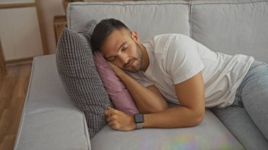 Sakallı yakışıklı bir İspanyol, oturma odasındaki bir kanepede uyuyor. Kafasını yastığa koyup, huzurlu ve rahat bir yüz ifadesi sergiliyor..