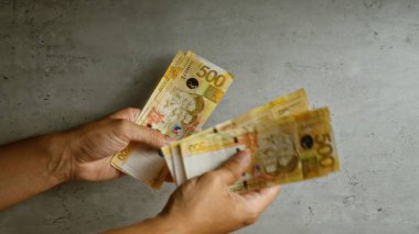 Elle sayılan filipin pesoları somut arka plan, vurgulama para birimi, 500 peso fatura ve finansal konsept.