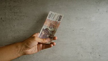 Gri beton arka planda İzlanda Krona banknotu tutan adam