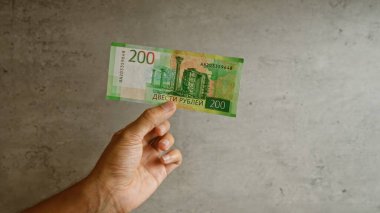 Beton duvara karşı el ele tutuşmuş Rus rublesi, modern para birimine odaklanmış, finansal konsepti gösteriyor.