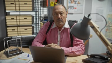 Ofis masasında bıyıklı olgun bir adam, geç saatlere kadar polis departmanında çalışıyor..