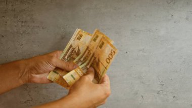 Man's hands counting norwegian krone banknotes against a concrete background, highlighting currency from norway clipart