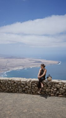 Lanzarote 'u gezen kadın, arka planda güzel bir kıyı manzarası olan kanarya adaları.