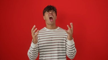 Hüsrana uğramış genç İspanyol bir adam, etkileyici bir portrede canlı kırmızı bir arkaplana bakarak çığlık atıyor..