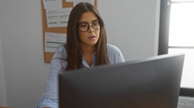 Ofiste çalışan İspanyol kadın bilgisayar ekranına bakarken ciddi bir ifade takınıyor..