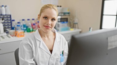 Laboratuvar önlüklü, kendine güvenen genç, sarışın bir kadın. Parlak bir laboratuarda çalışıyor, profesyonelliği canlandırıyor.