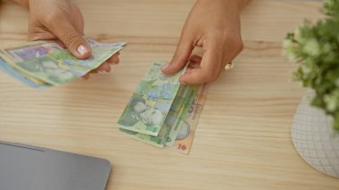Bir kadın, bir fabrikanın yakınındaki ahşap bir masadaki Romen leu banknotlarını sayıyor..