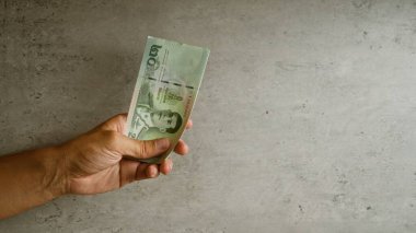 Tayland 'da para transferini temsil eden somut bir arkaplanda Thai baht parası tutuluyor.