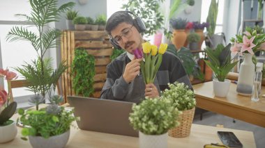 Çiçek ve çiçeklerle dolu bir çiçekçide lale kokusu alan kulaklıklı İspanyol bir adam..
