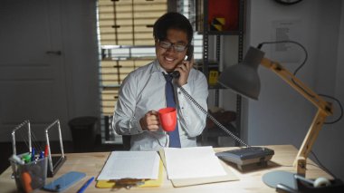 Asian man in detective office on phone with coffee, evidence around him in indoor setting clipart