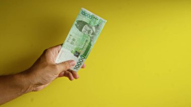 El ele tutuşan Koreli, sarı arka planda Kore para birimini göstererek kazandı..