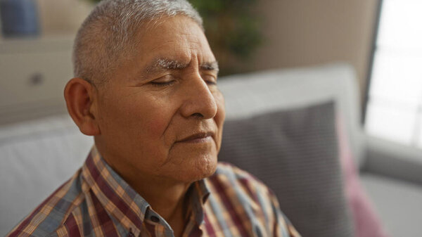 A grey-haired hispanic man peacefully rests in his living room with his eyes closed, showcasing a calm and serene interior setting.
