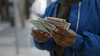 A woman counting uae dirham currency notes on an urban street. clipart