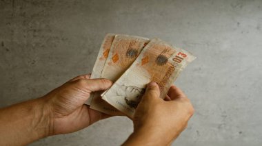 İngiliz kilolarını beton zemine dayayan eller, İngiliz paralarını doğal ışık altında sergiliyor..