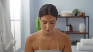 Kapalı bir salonda dinlenen, sakin dekorları ve hafif ışıklandırmaları olan, güzelliğini ve sakin tavırlarını sergileyen bir kadın.