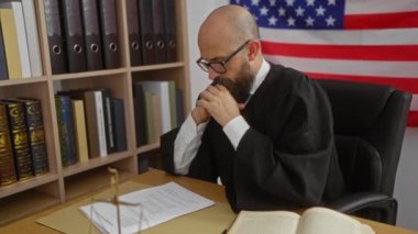 Ofisteki stresli yargıç, arka planda Amerikan bayrağı ve kitaplarla doküman okuyor.