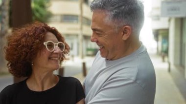 Orta yaşlı bir çift, şehir merkezinde bir sokakta gülüyor ve eğleniyorlar..