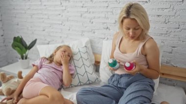 Anne ve kız yatak odasında ilaç şişelerine bakan bir kadınla çocuk doldurulmuş bir oyuncakla yatakta yatarken.