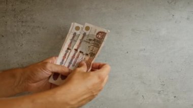 Mısır 'da para ve finansman odaklı finansal bir temayı betimleyen, beton bir arka plan karşısında Mısır sterlini tutan eller