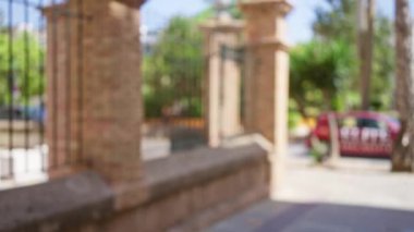 Açık hava parkında güneşli bir günde bulanık tuğlalı çitlerin ve ağaçların olduğu kentsel bokeh sahnesi.