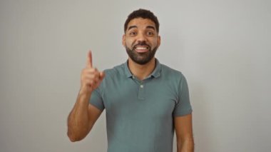 Genç İspanyol bir adam fikirle ayakta duruyor, bir parmağını mutlu bir şekilde kaldırıyor, izole edilmiş beyaz arka plan üzerinde bir numaralı başarıyı işaret ediyor.