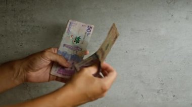 Kolombiyalı bir adam, Kolombiya 'daki para birimini vurgulayan beton bir duvar arkasında Kolombiya pezosu tutuyor.